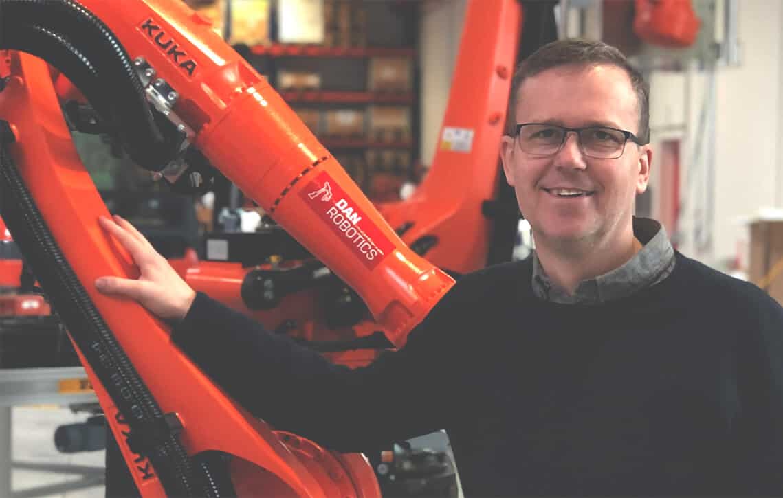Billede af MIchael Friis med KUKA robotter i baggrunden.